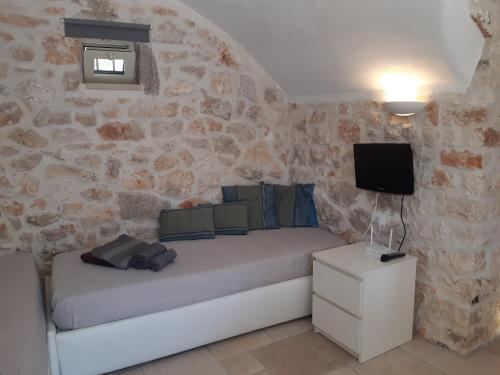 - une chambre avec un lit et un mur en pierre dans l'établissement Antico Trullo Ulmo, à Ceglie Messapica