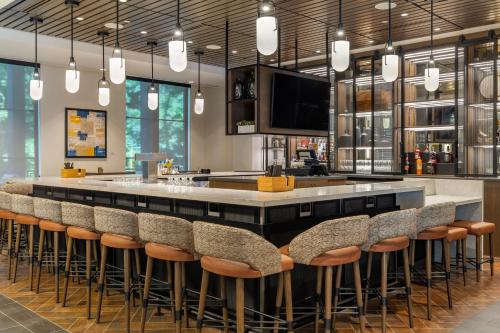 a bar with stools in a room with a tv at Cambria Hotel New Haven University Area in New Haven