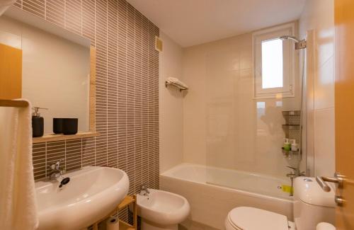 łazienka z wanną, umywalką i toaletą w obiekcie Area Suites w mieście Jove