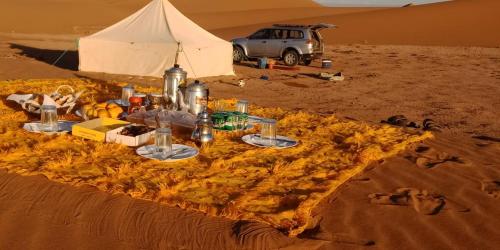 Tikida Camp by tinfou في زاكورة: طاولة في وسط صحراء مع خيمة