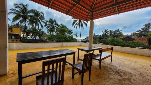 two tables and chairs on a balcony with palm trees at Hostel Mandala in Anjuna