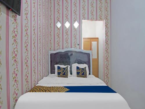 Bett mit zwei Kissen in einem Zimmer mit Tapete in der Unterkunft OYO 91826 Yoezef Homestay Syariah in Pekanbaru