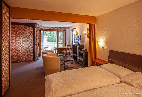 a hotel room with a bed and a living room at Hotel Astoria in Leukerbad