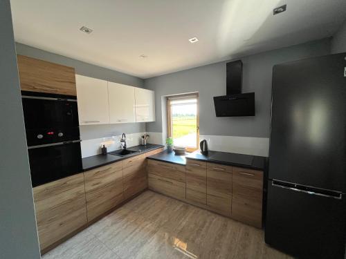 a kitchen with wooden cabinets and a black refrigerator at Osada Marcowa - Niebieski Domek z sauną & jacuzzi in Zakopane