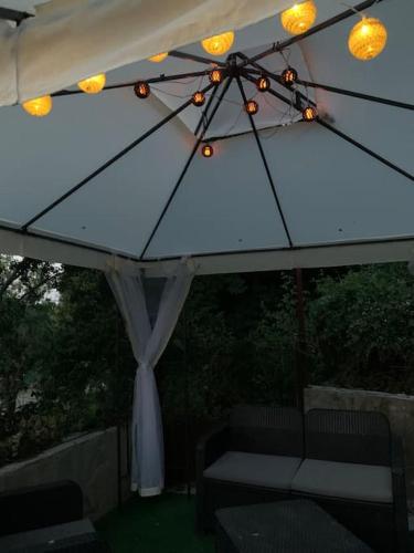 a white umbrella with lights and a couch under it at Maisonnette atypique cadarache-iter in Saint-Paul-lez-Durance