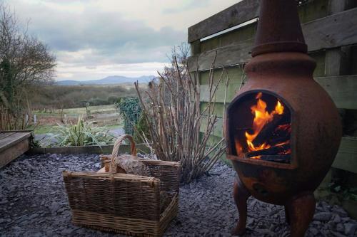 a brick fireplace next to two baskets at Tyddyn Plwm Isa in Newborough