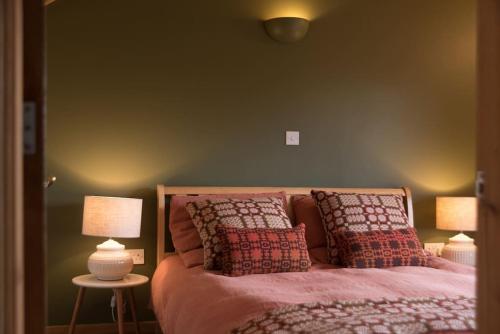 - une chambre avec un lit avec des oreillers et 2 lampes dans l'établissement Tyddyn Plwm Isa, à Newborough