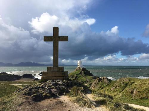 a cross on top of a hill next to the ocean at Tyddyn Plwm Isa in Newborough