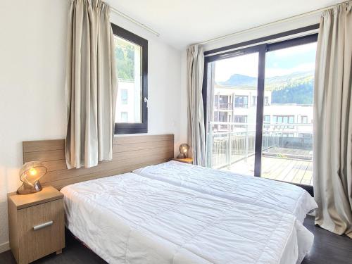 une chambre avec un lit et une grande fenêtre dans l'établissement Appartement Lumineux au Pied des Pistes avec Piscine, Parking, Spa et Grande Terrasse - FR-1-425-18, à Flaine