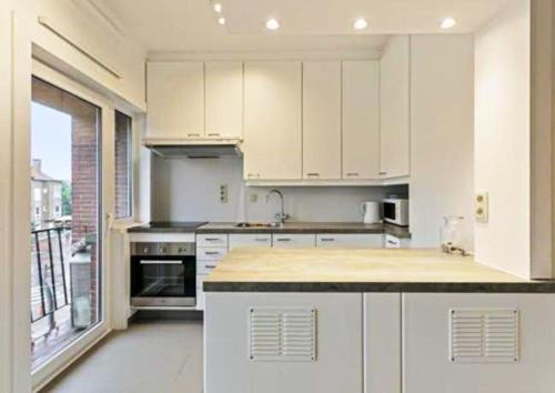 een keuken met witte kasten en een groot raam bij 2 bedrooms appartement with city view balcony and wifi at Knokke Heist in Zeebrugge