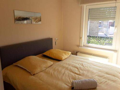 uma cama com duas almofadas num quarto com uma janela em 2 bedrooms appartement with city view balcony and wifi at Knokke Heist em Zeebrugge