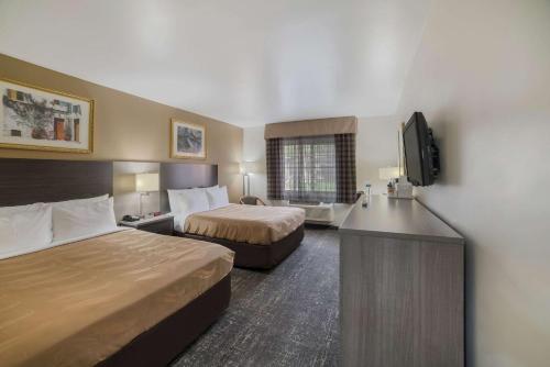 a hotel room with two beds and a flat screen tv at Quality Inn & Suites Goodyear - Phoenix West in Goodyear