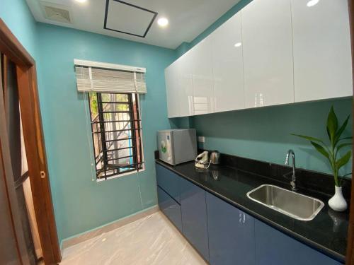 cocina con paredes azules, lavabo y ventana en Siem Reap Homesteading, en Siem Reap