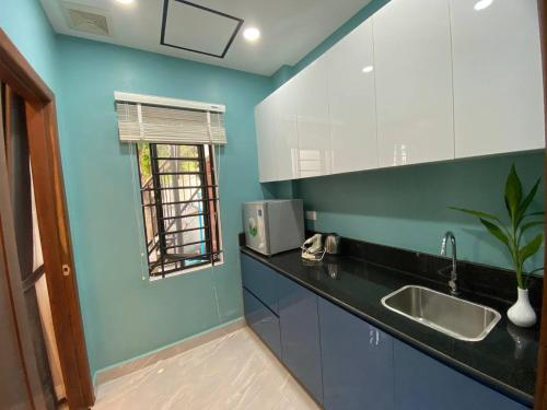 a kitchen with blue walls and a sink and a window at Siem Reap Homesteading in Siem Reap