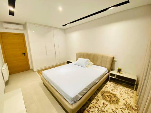a small bedroom with a bed and a door at Sousse Sahloul apartment de luxe 10 min de la mer in Sousse