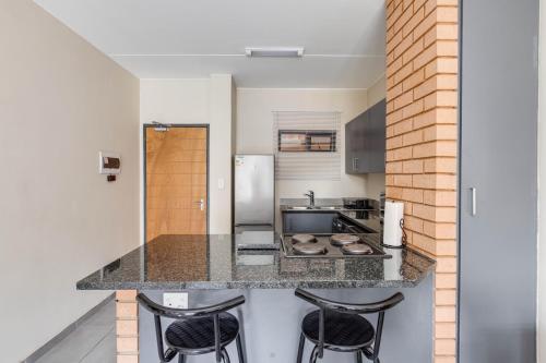 a kitchen with a counter with three stools at The Resting Nest Havilla in Midrand