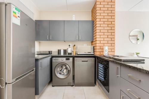 a kitchen with gray cabinets and a washer and dryer at The Resting Nest Havilla in Midrand