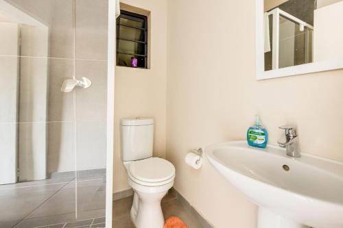 a white bathroom with a toilet and a sink at The Resting Nest Havilla in Midrand