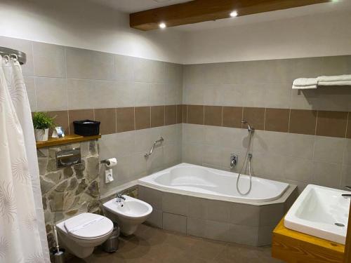 a bathroom with a tub and a toilet and a sink at Penzion Venuša in Spišská Nová Ves