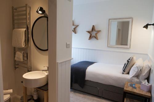 a bedroom with a bed and a sink and a mirror at The Victoria in Alderney