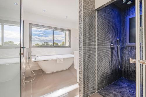 een badkamer met een bad en een douche met een raam bij Villa Massane in Baillargues