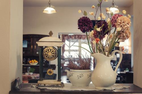 a table with a vase of flowers and a clock at Hotel Na Skalkách in Nový Jičín