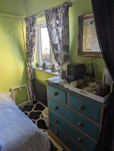 a bedroom with a blue dresser and a window at Quaint & Quirky House Colchester Town Centre in Colchester