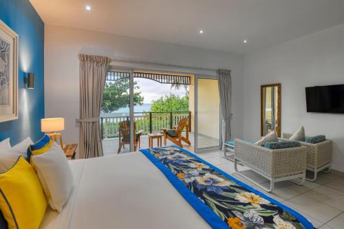a bedroom with a large bed and a balcony at Acajou Beach Resort in Baie Sainte Anne