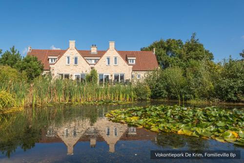 a house in the middle of a pond with lilies at Vakantiepark De Krim Texel in De Cocksdorp