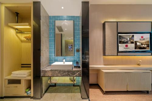 a bathroom with a sink and a mirror at Echarm Hotel Foshan Guangfo Road Jiaokou Metro Station in Foshan