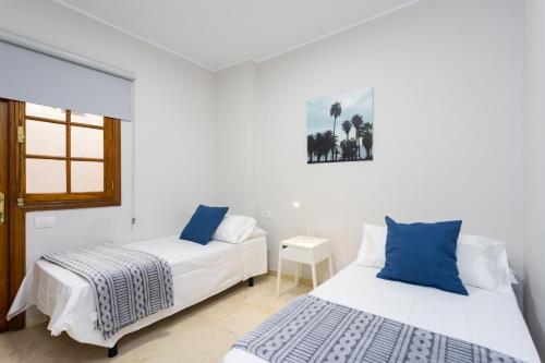 Home2Book Santa Cruz Skyline Comfy Apartment في سانتا كروث دي تينيريفه: سريرين في غرفة بيضاء مع نافذة