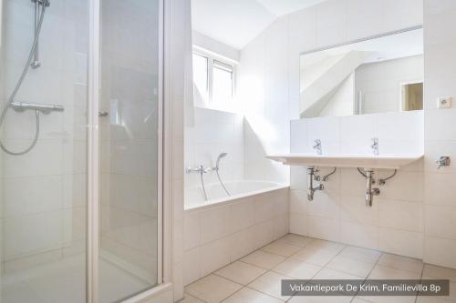 a white bathroom with a shower and a sink at Vakantiepark De Krim Texel in De Cocksdorp