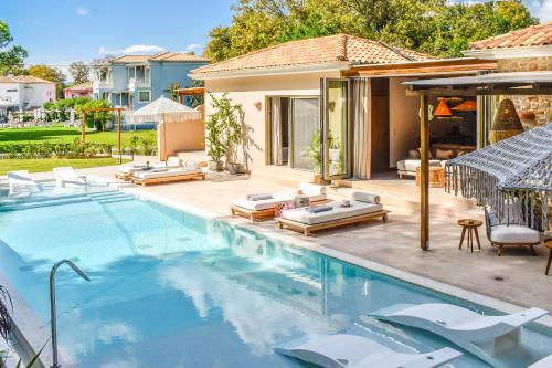 a swimming pool with chairs and a house at Mandraki Village Boutique Hotel in Koukounaries