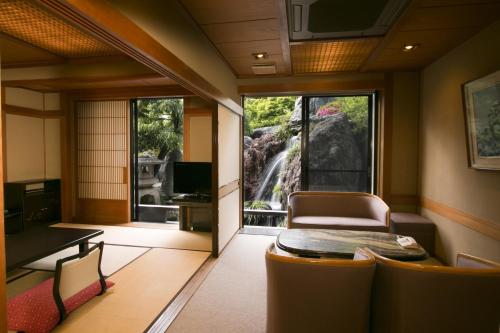 a living room with a view of a waterfall at Beautiful Japanese Garden Kagetsu in Fuefuki