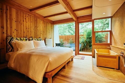 輕井澤的住宿－SHISHI-IWA-HOUSE Karuizawa，卧室配有床、浴缸和窗户。