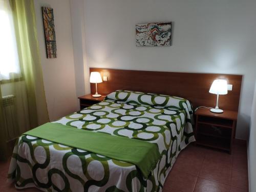 a bedroom with a green and white bed and two lamps at Apartamentos la Escuela en Cantabria in Villegar