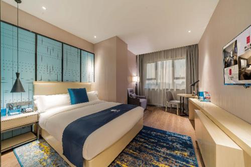 a hotel room with a large bed and a desk at Echarm Hotel Foshan Guangfo Road Jiaokou Metro Station in Foshan