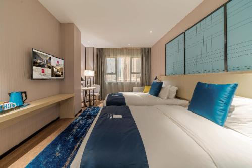 a large bedroom with two beds with blue pillows at Echarm Hotel Foshan Guangfo Road Jiaokou Metro Station in Foshan