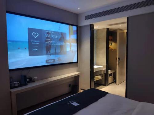 a bedroom with a large flat screen tv on the wall at Echarm Hotel Foshan Guangfo Road Jiaokou Metro Station in Foshan