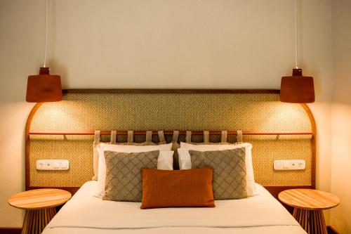 a bedroom with a large bed with two tables at Mandraki Village Boutique Hotel in Koukounaries