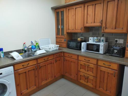 a kitchen with wooden cabinets and a sink and a microwave at Lucker mill shepherds huts in Lucker