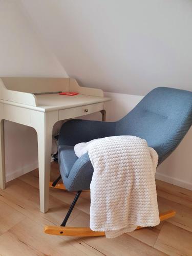a blue chair sitting next to a desk with a blanket at Domek na Polanie in Ustroń