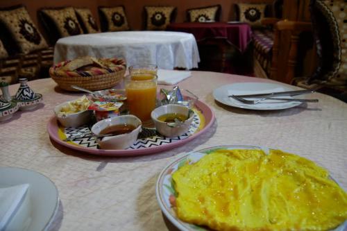 einen Tisch mit einem Teller mit Speisen und Getränken darauf in der Unterkunft La Belle étoile in Aït Oussane