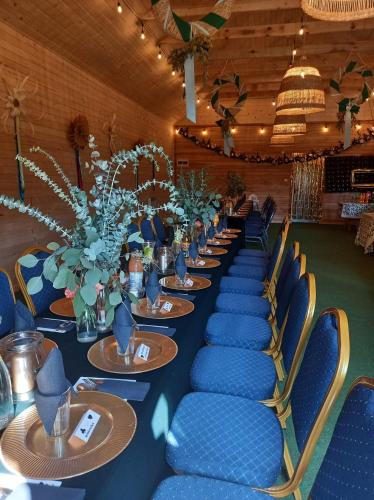 a long table with blue chairs and plates and flowers at Wioska pod Kogutem in Krępa