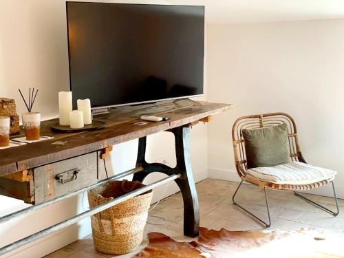 a desk with a television on top of it with a chair at La Maison de Lyna - Suites de charme intra-muros avec parking & autonomie in Aigues-Mortes