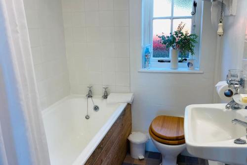 y baño con bañera, aseo y lavamanos. en Benwick Cottage - Beachfront Thatched Cottage set on the marine parade with absolutely spectacular Sea views! Sleeps 4, en Lyme Regis