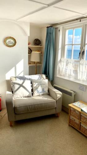 a living room with a couch and a window at Benwick Cottage - Beachfront Thatched Cottage set on the marine parade with absolutely spectacular Sea views! Sleeps 4 in Lyme Regis
