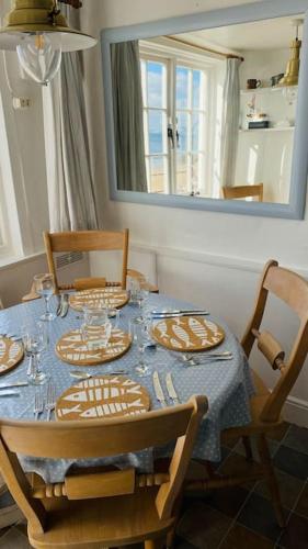 a dining room table with plates and glasses on it at Benwick Cottage - Beachfront Thatched Cottage set on the marine parade with absolutely spectacular Sea views! Sleeps 4 in Lyme Regis