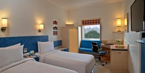 a hotel room with two beds and a desk at Nirwana Hometel Jaipur- A Sarovar Hotel in Jaipur