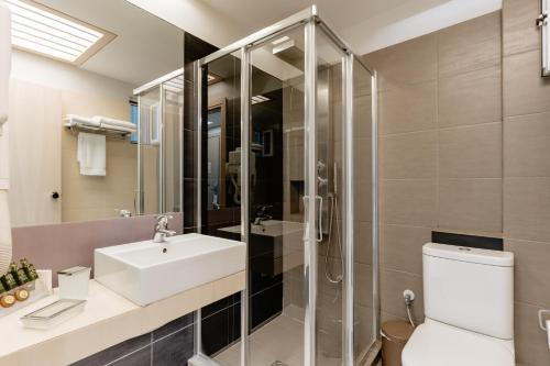a bathroom with a shower and a sink and a toilet at Palm Beach Hotel Apartments in Rethymno Town